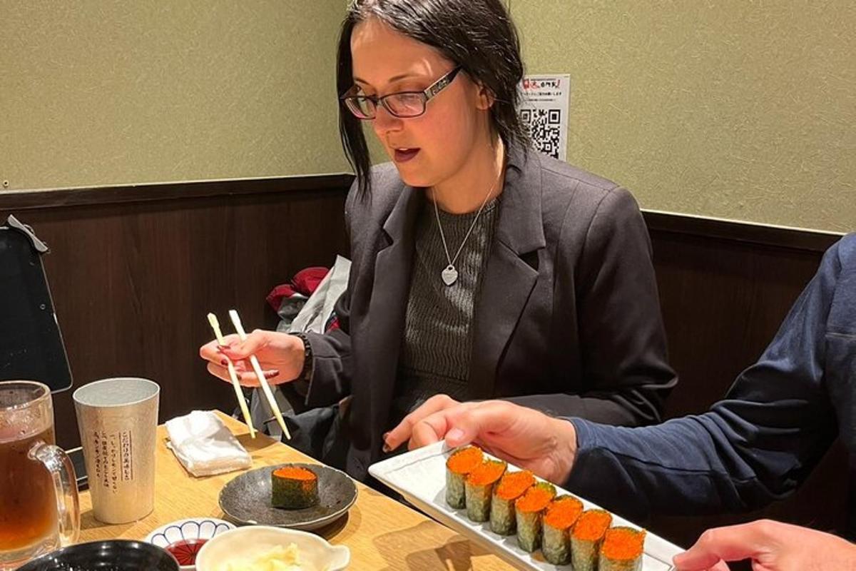 một người phụ nữ đang ngồi ở bàn ăn sushi bằng đũa
