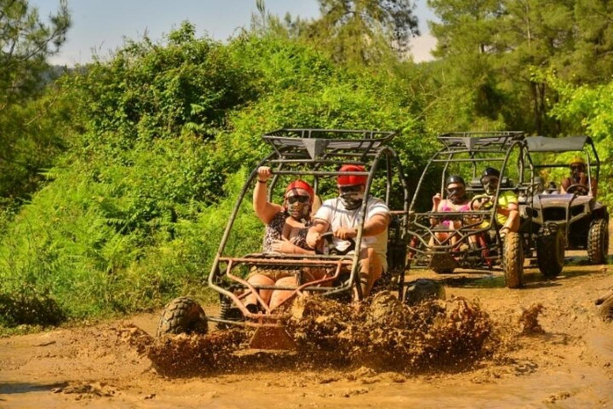 skupina lidí jedoucích na čtyřkolce v bahně