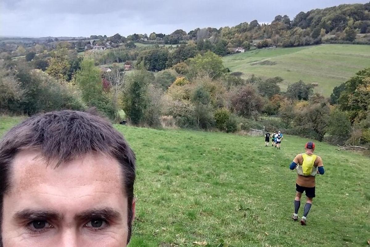 Un hombre parado en un campo con gente caminando por una colina.