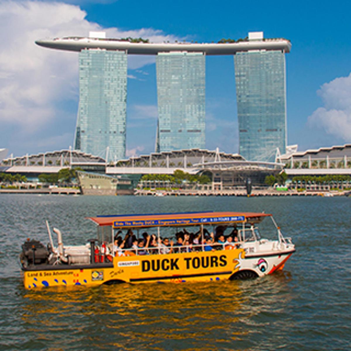 um barco turístico de pato amarelo na água com edifícios