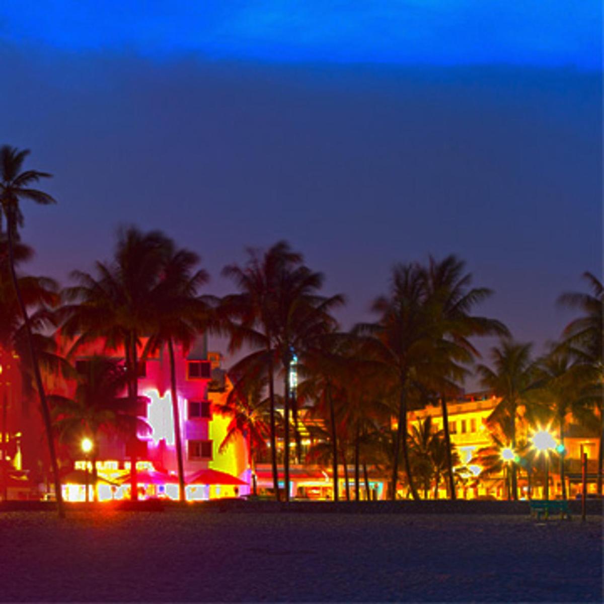 a resort with palm trees and a building at night