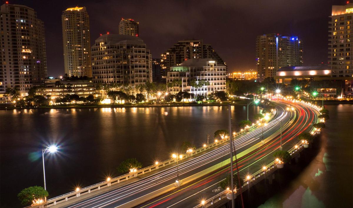 a city lit up at night with traffic on a highway