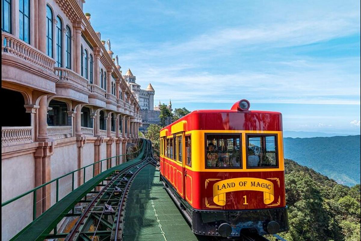 Ένα κόκκινο και κίτρινο τρένο σε γραμμές δίπλα σε ένα κτίριο