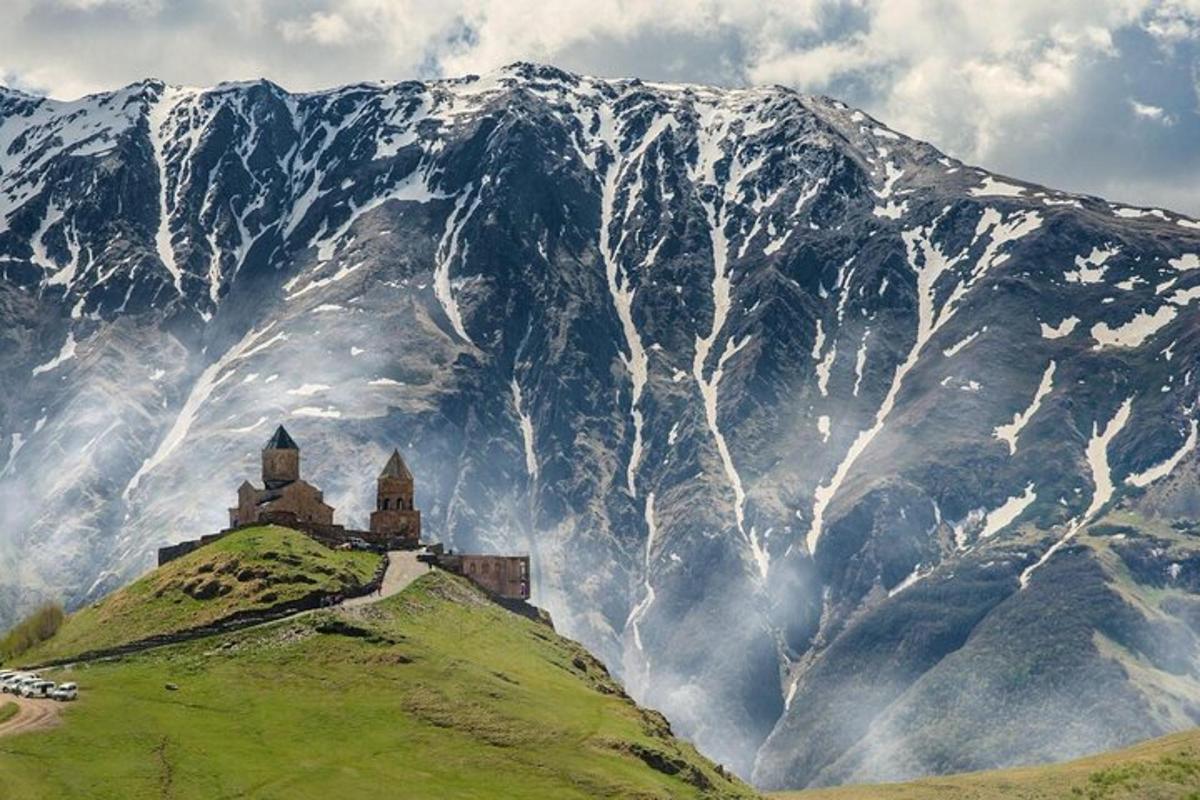 a castle on a hill in front of a mountain