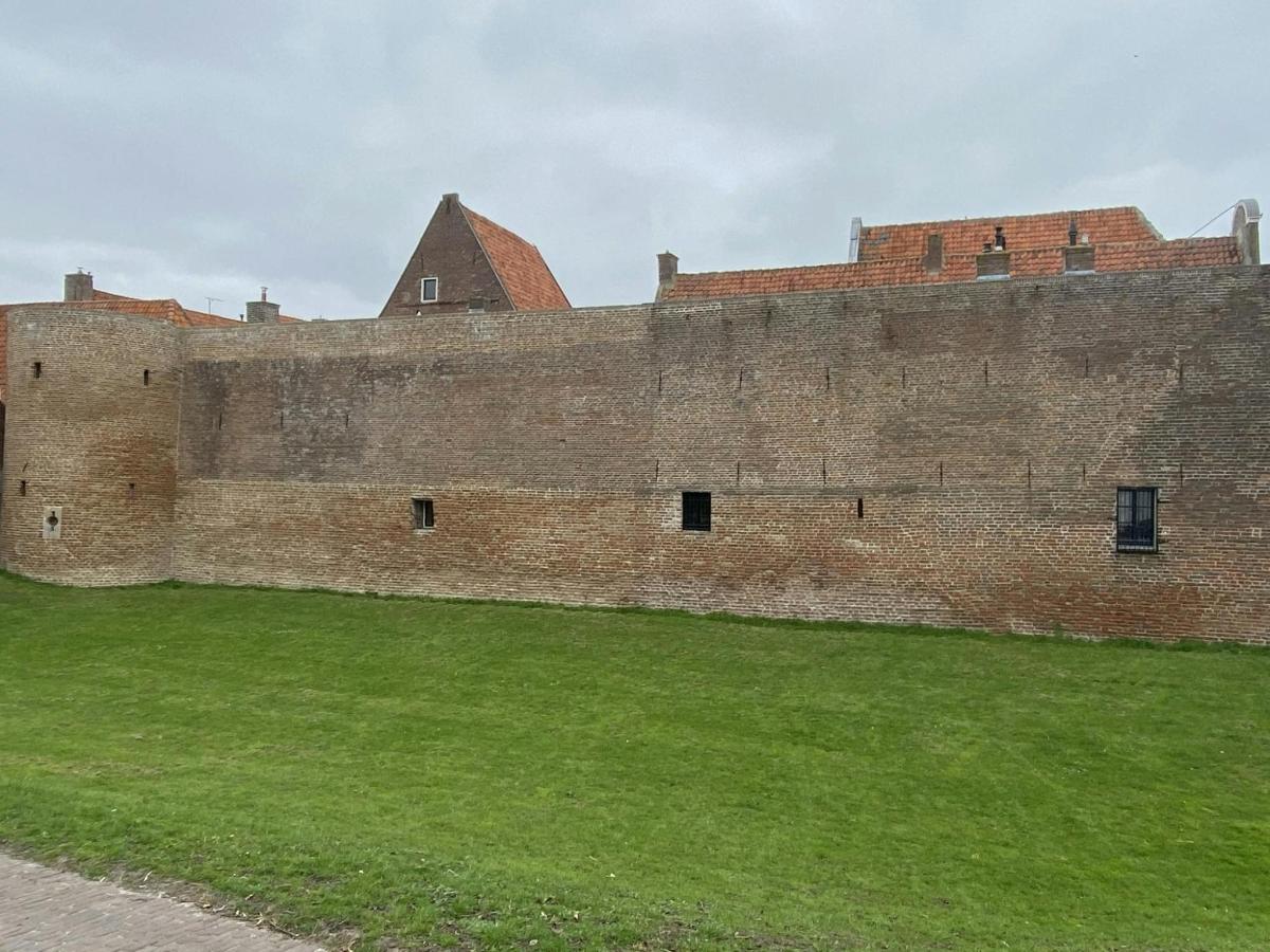 egy nagy téglafal, előtte zöld fűvel