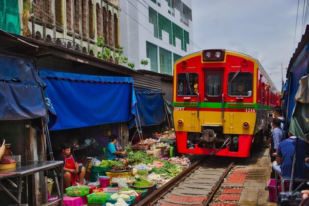 um trem vermelho e amarelo nos trilhos ao lado de um mercado