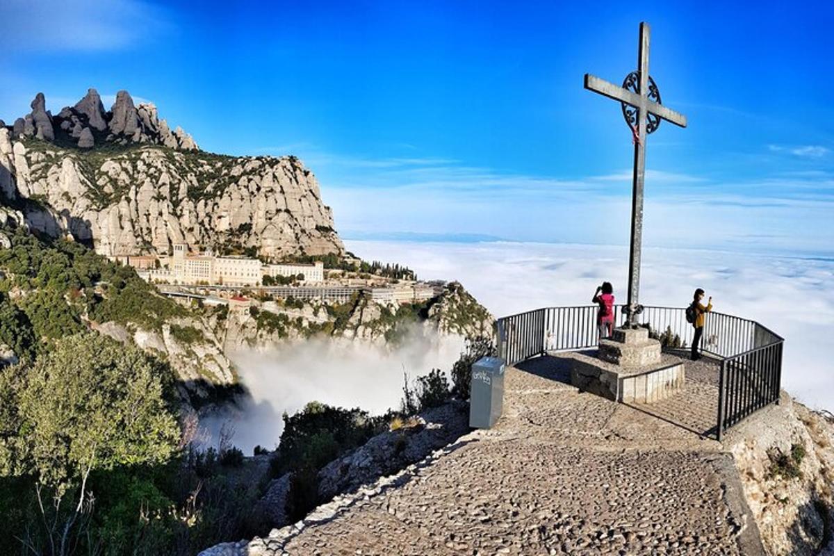 a cross on the side of a mountain with people standing on it
