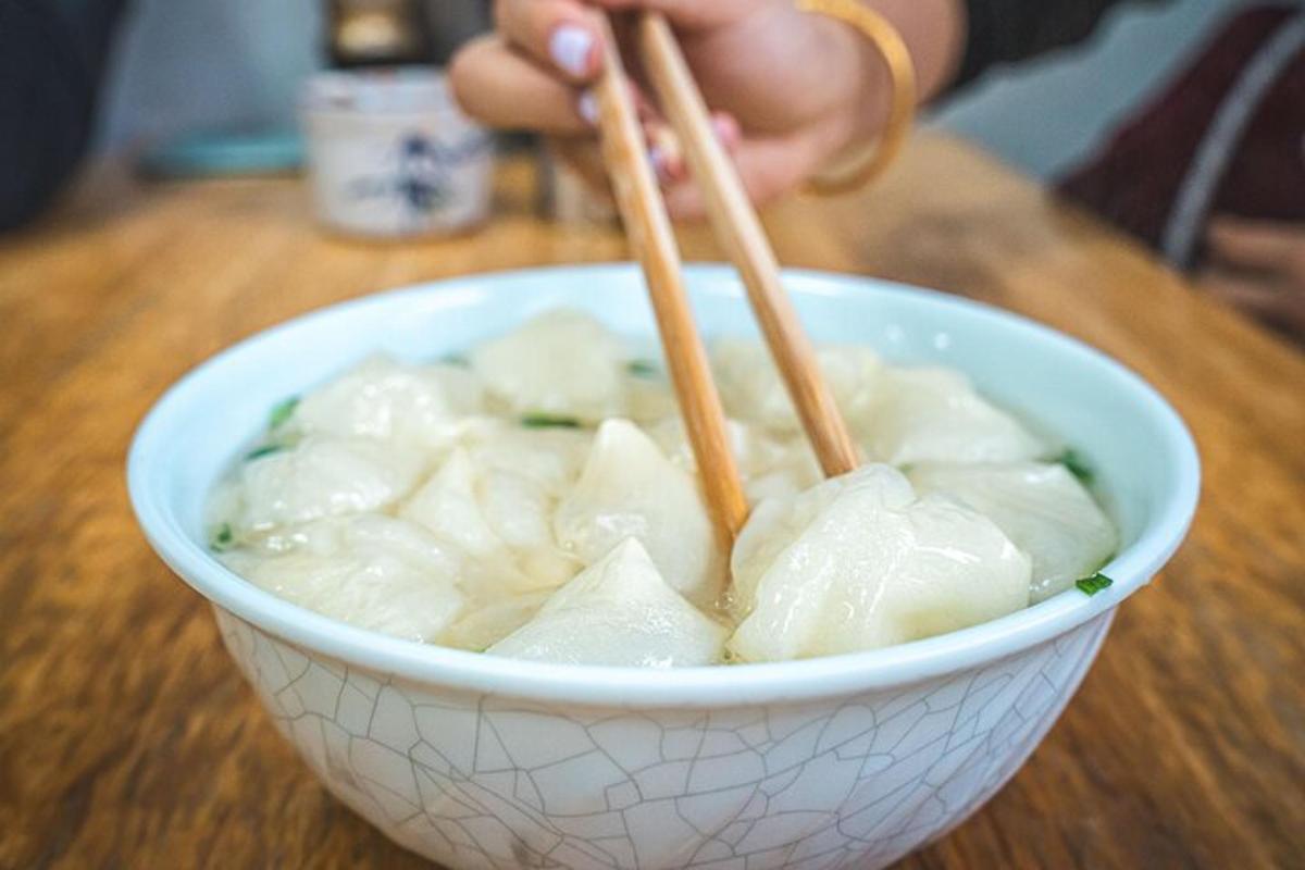 a person holding chopsticks in a bowl of food