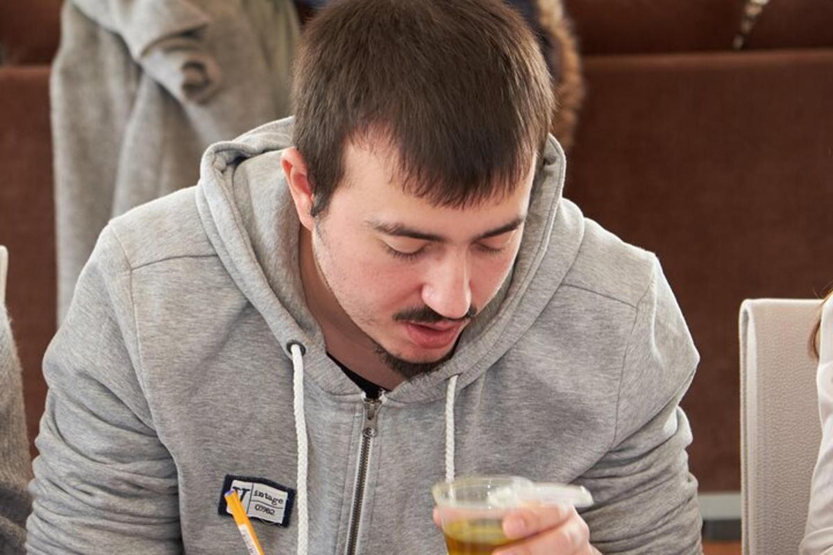 mężczyzna w szarej bluzie z kapturem trzymający napój