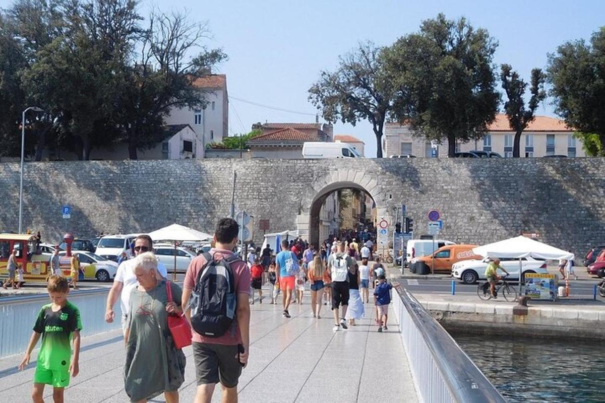 a group of people walking on a sidewalk near the water