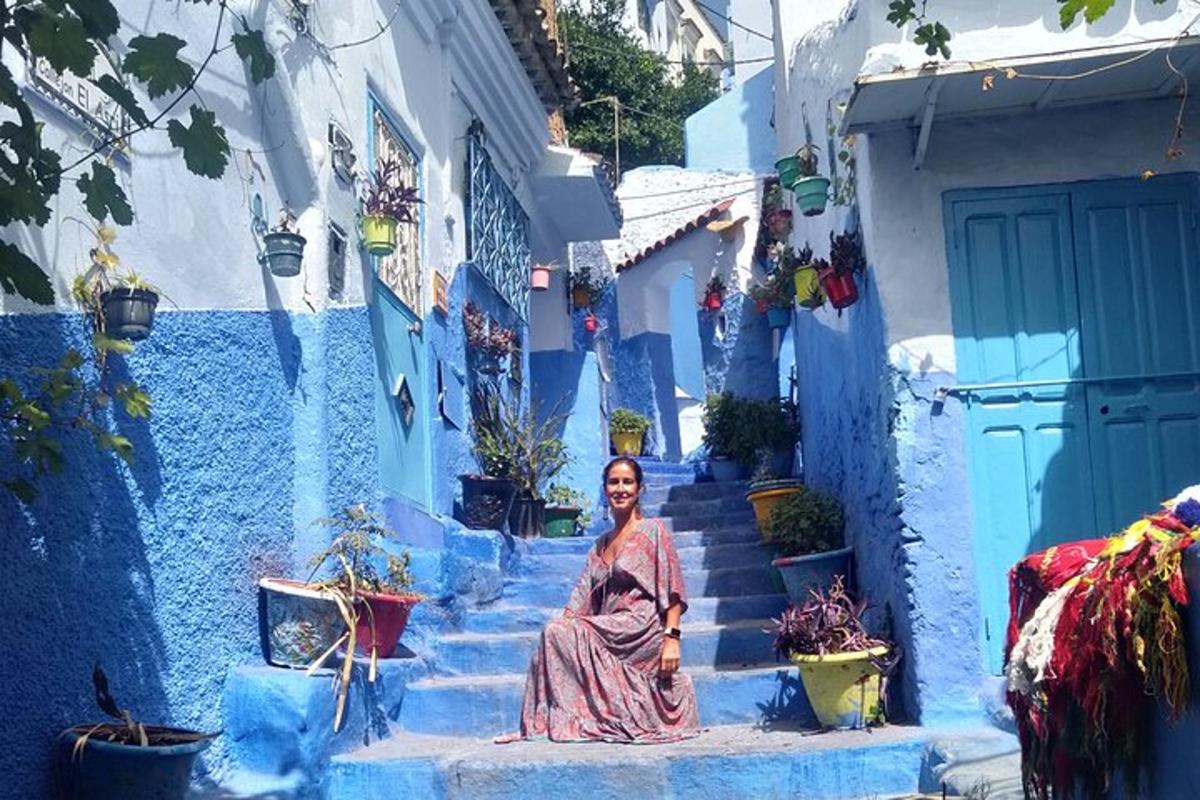 una dona asseguda a les escales d'un carreró blau
