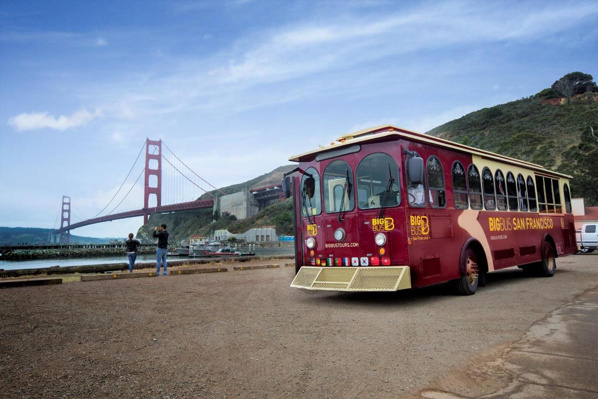 Červený autobus parkuje před mostem