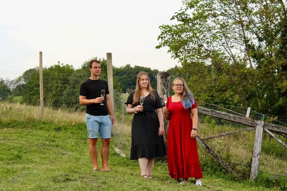 drei Personen stehen auf einem Feld und halten Weingläser