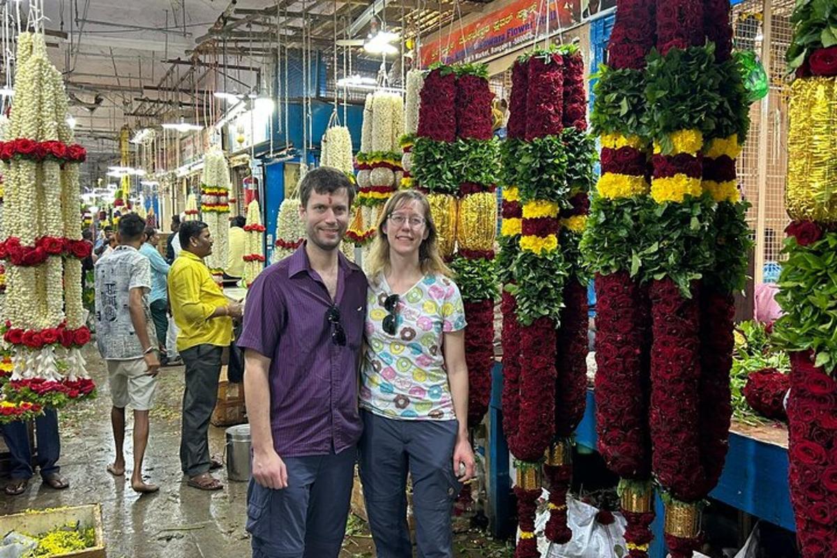 a man and woman standing in a market with flowers