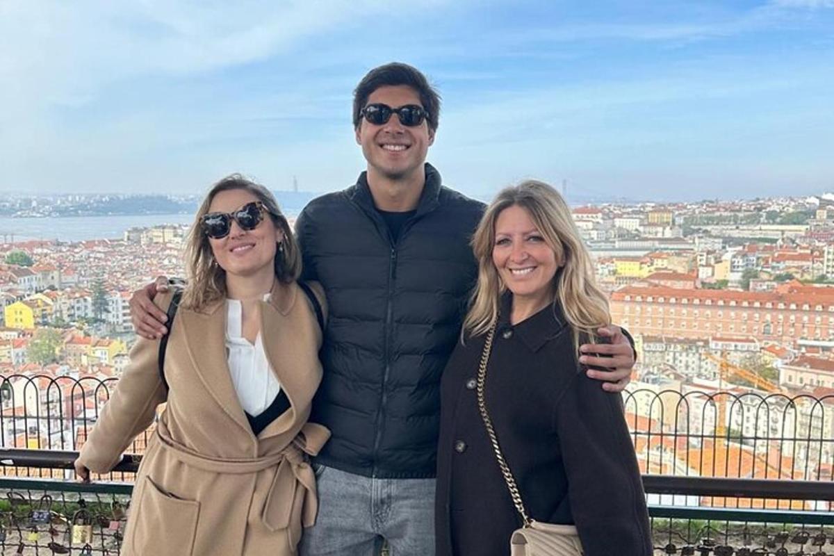 un home i dues dones posant per a una foto davant d'una ciutat
