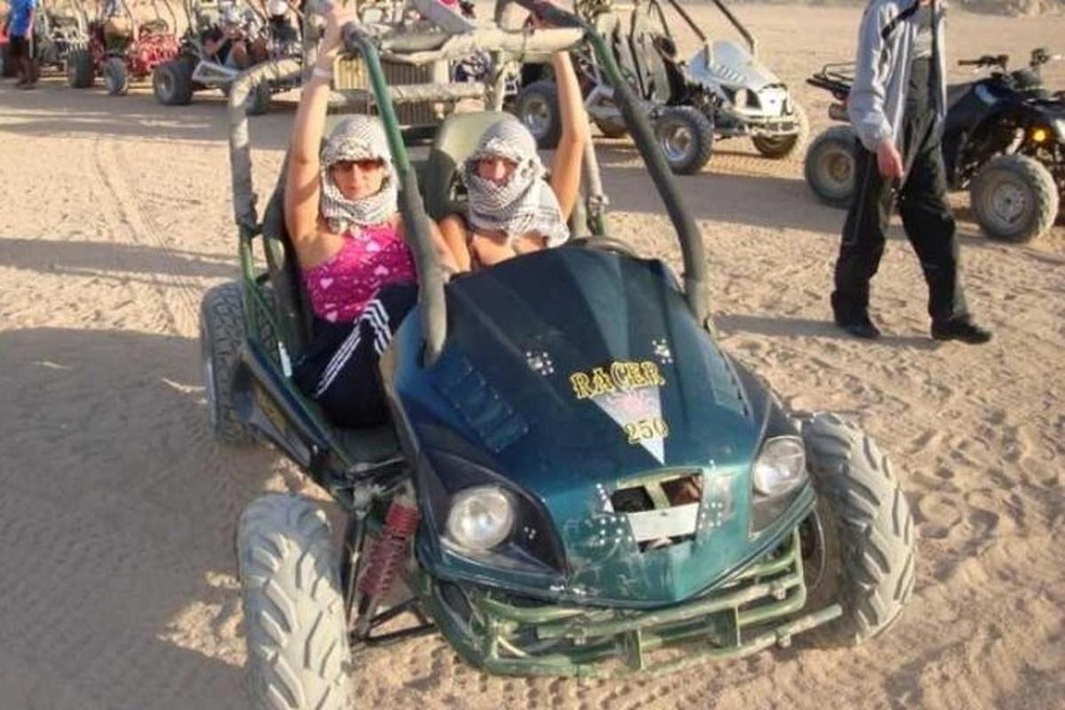 dalawang tao na nakasakay sa isang four wheeler sa dalampasigan