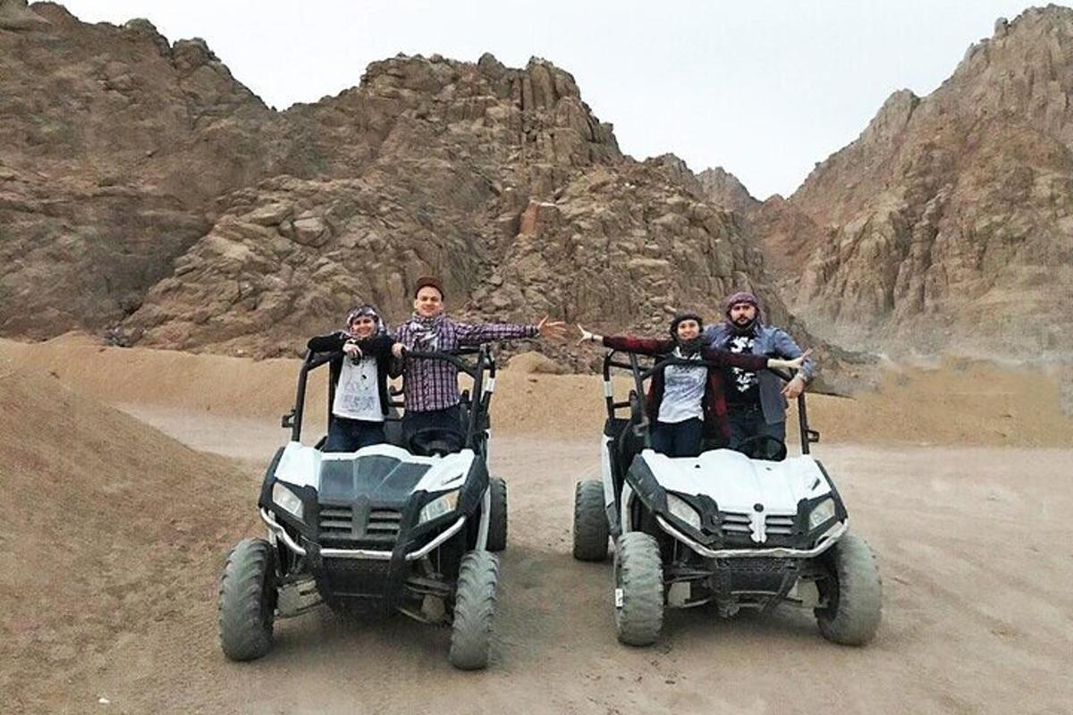 a group of people standing on four wheelers in the desert