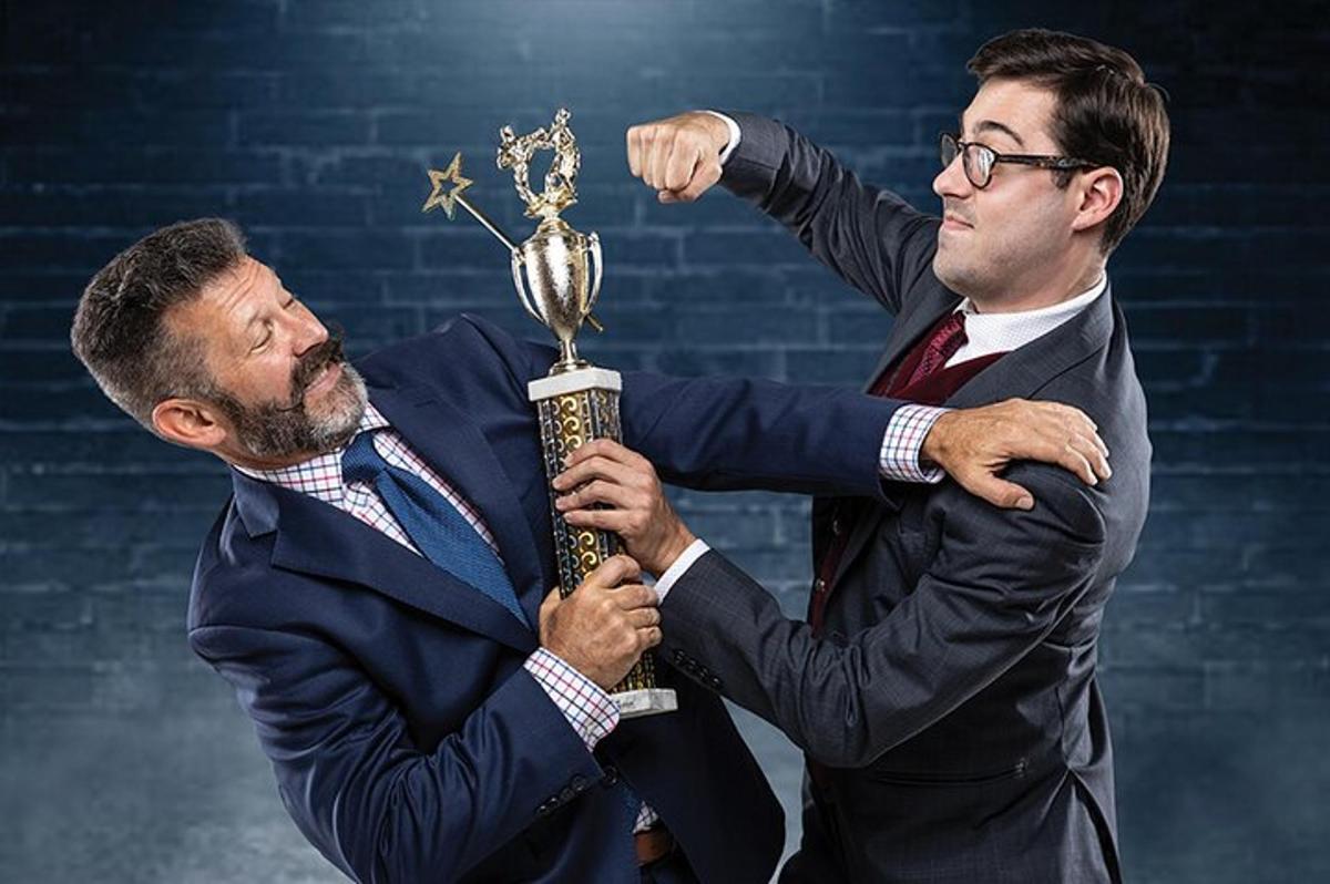 dva moška v oblekah držita pokal