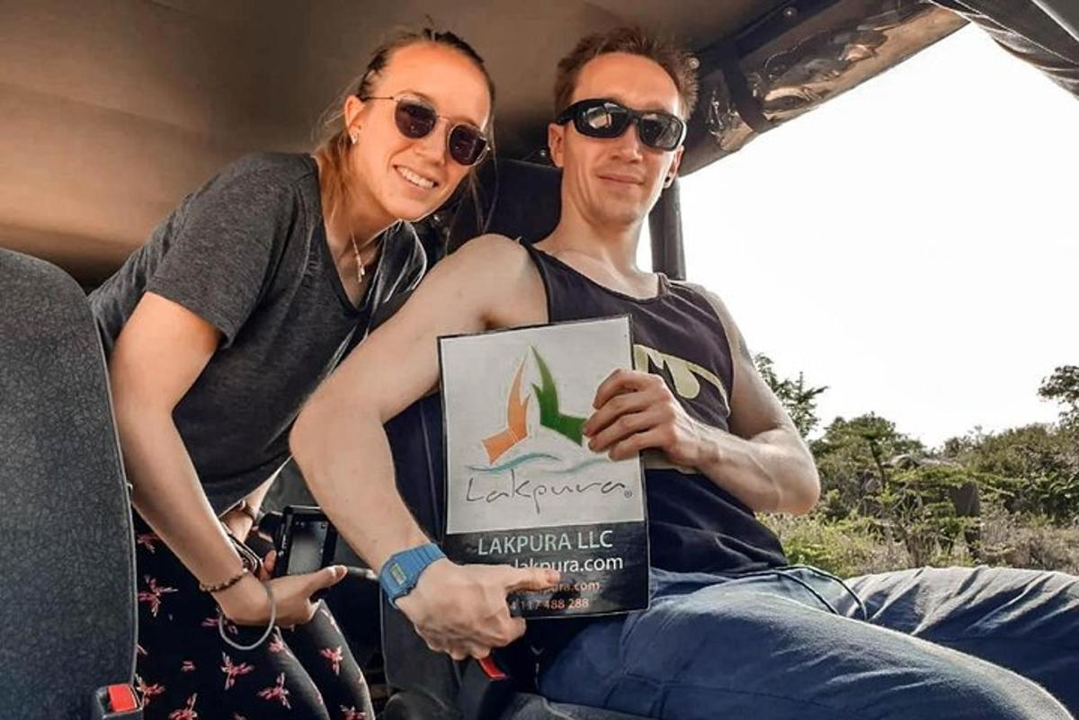 a man and woman sitting in a vehicle holding a sign