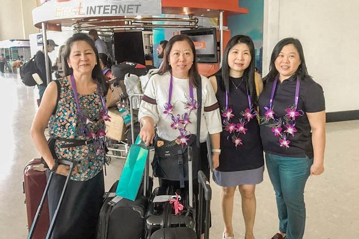 four women are standing with their luggage at an airport