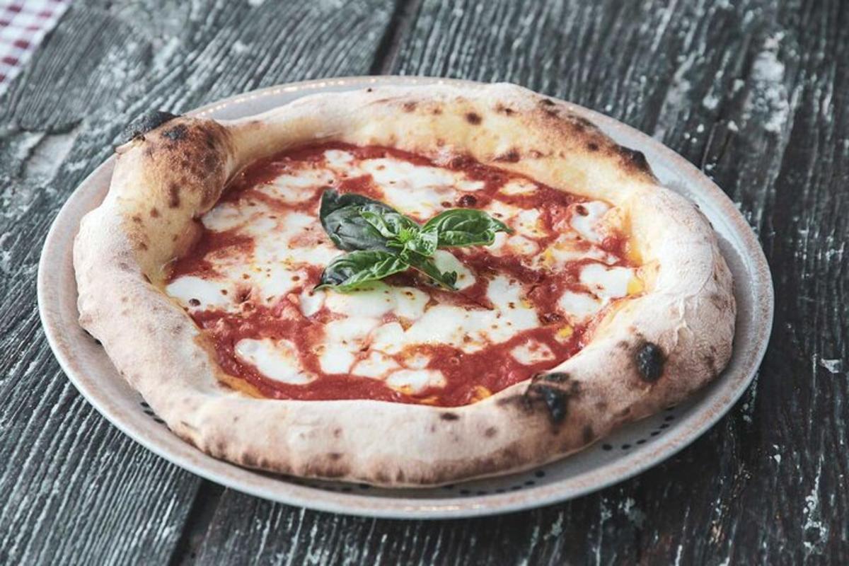 Una pizza pequeña en un plato sobre una mesa de madera.