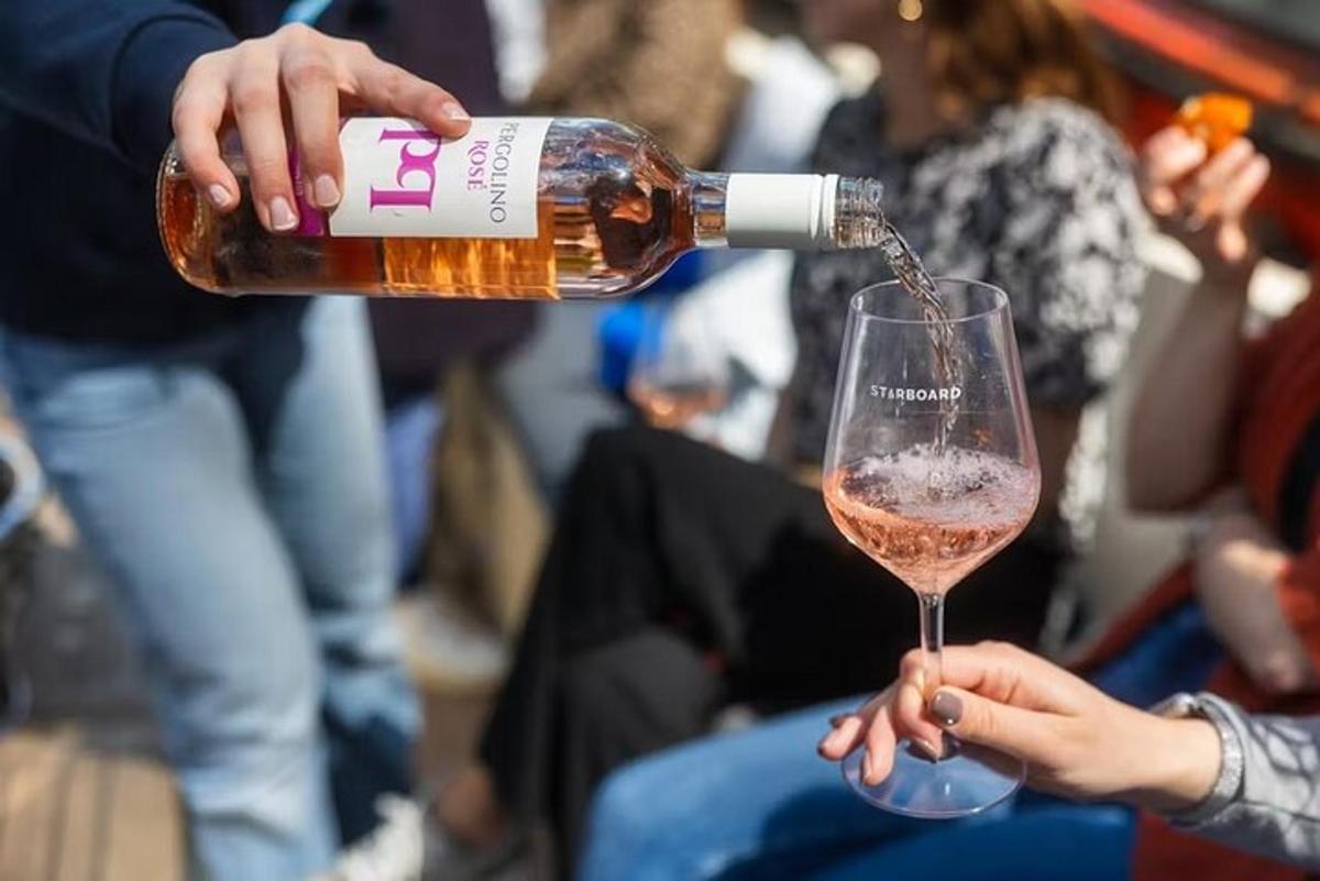 uma pessoa despejando uma garrafa de vinho em um copo