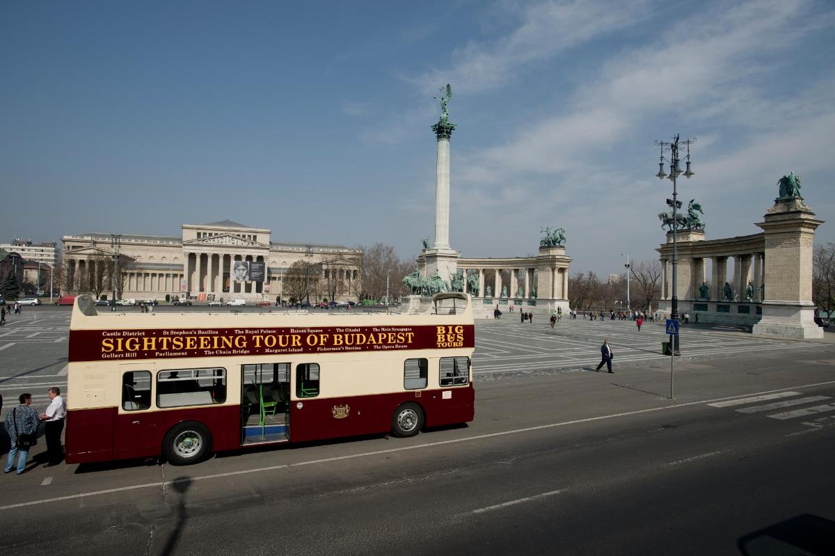 a red and white bus in front of a monument