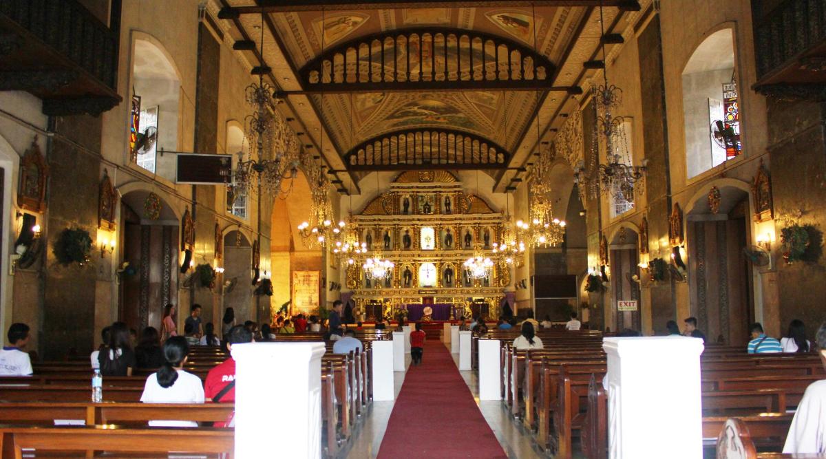 una grande chiesa con banchi e persone sedute al suo interno