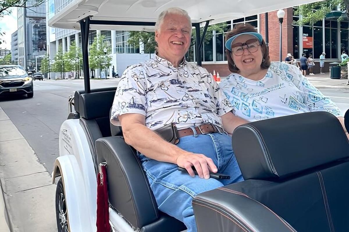 an older man and woman riding in a golf cart