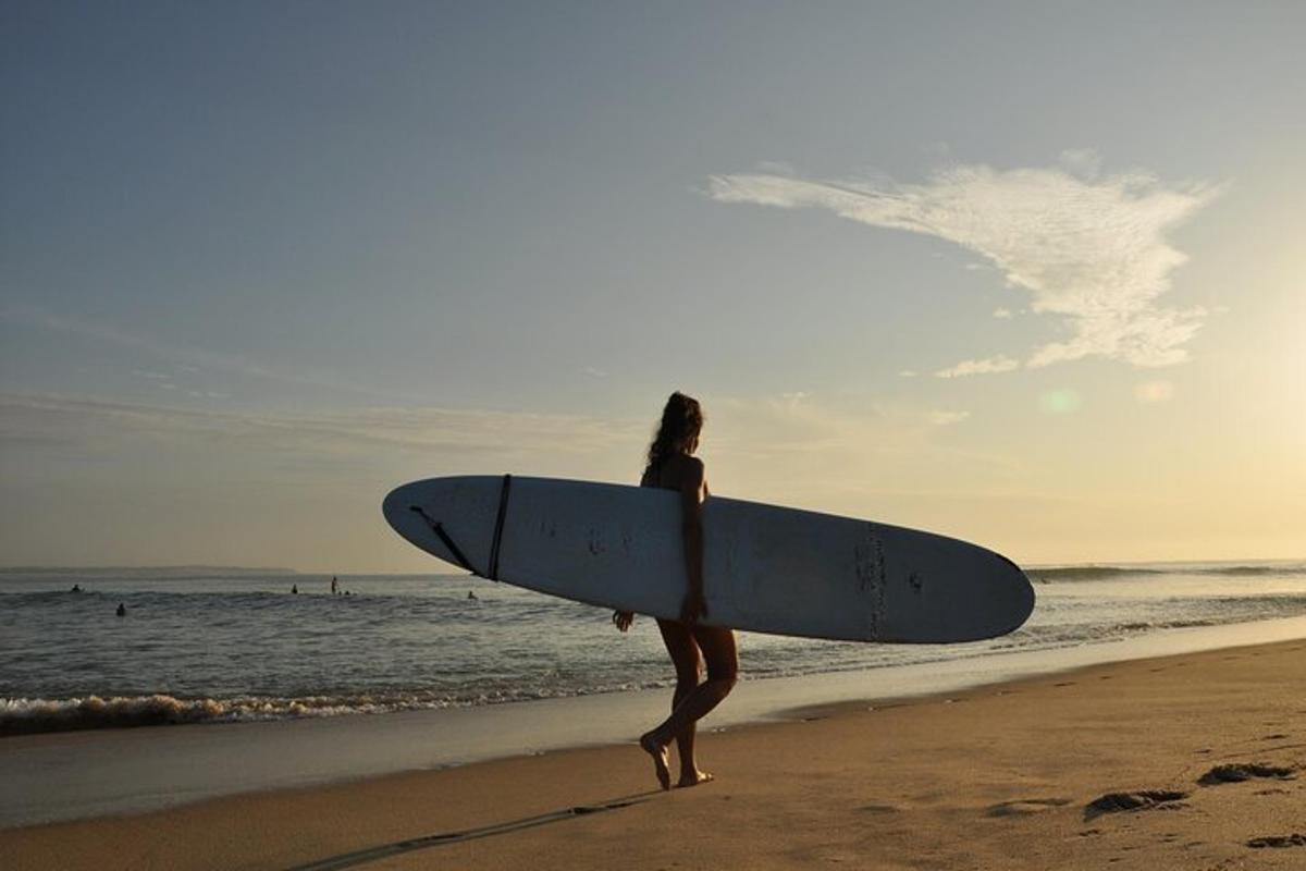 ผู้หญิงยืนอยู่บนชายหาดถือกระดานโต้คลื่น
