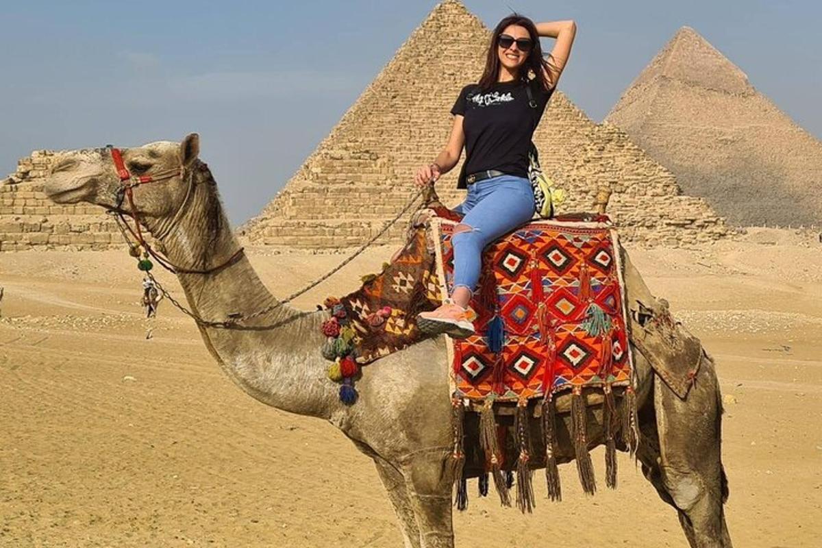 a woman riding on a camel in front of the pyramids