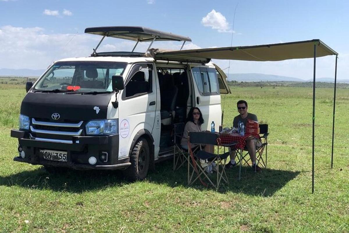 Un hombre y una mujer sentados en una mesa frente a una camioneta.