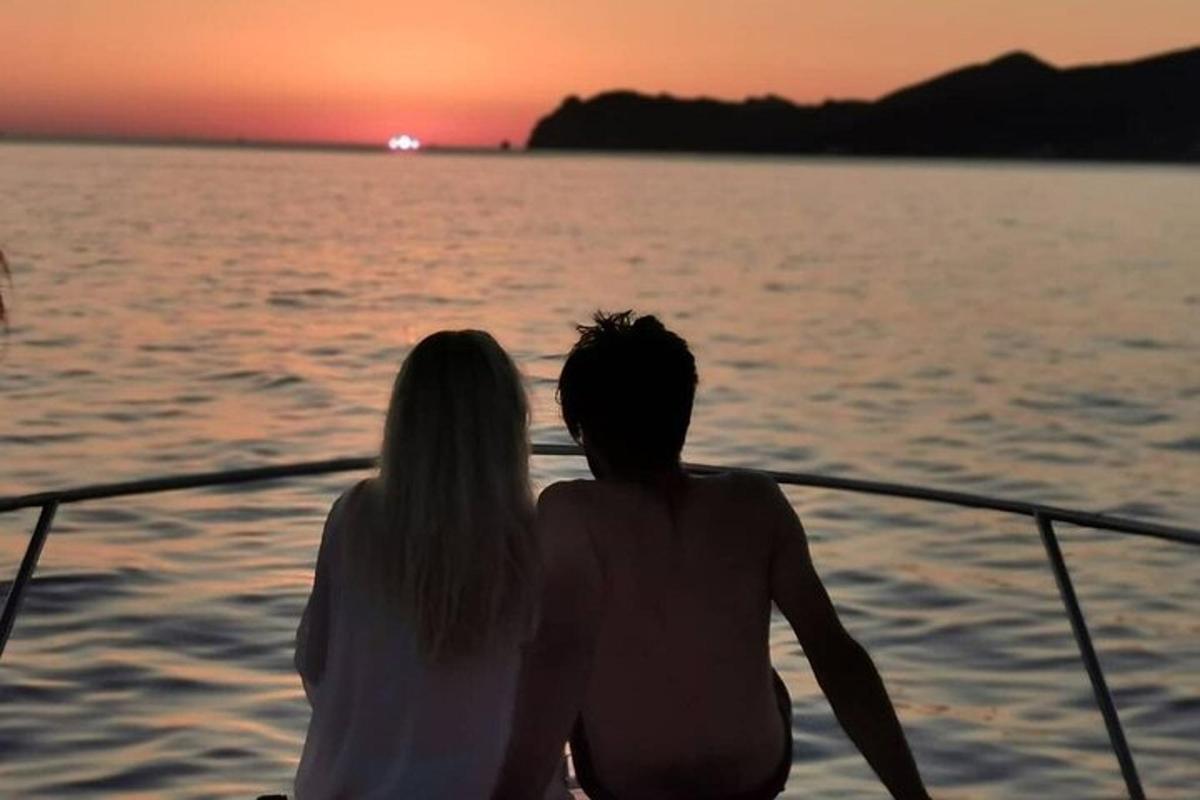 a couple sitting on a boat watching the sunset