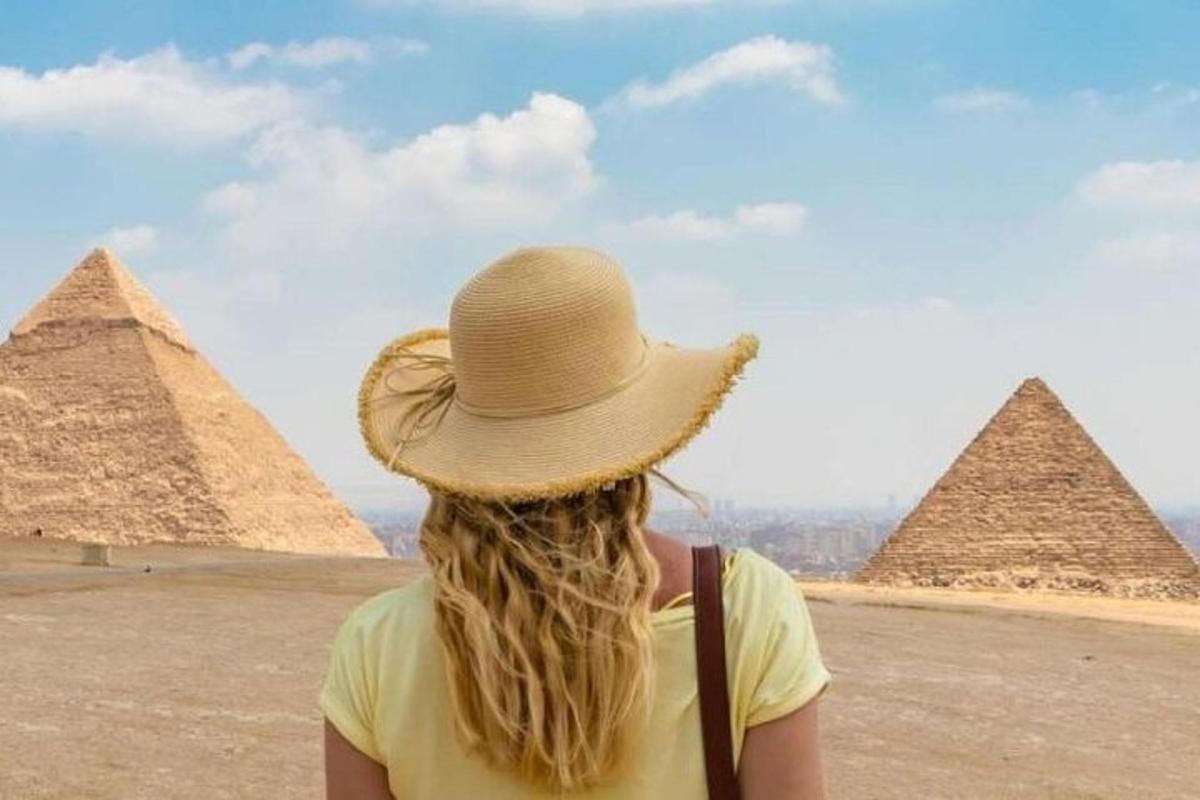Una mujer con un sombrero de paja mirando las pirámides.