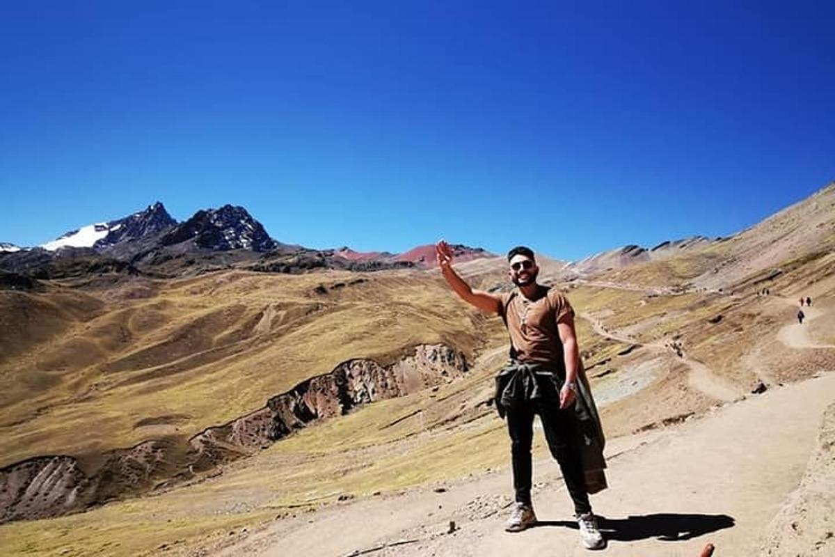 seorang lelaki berdiri di atas gunung dengan tangannya di udara
