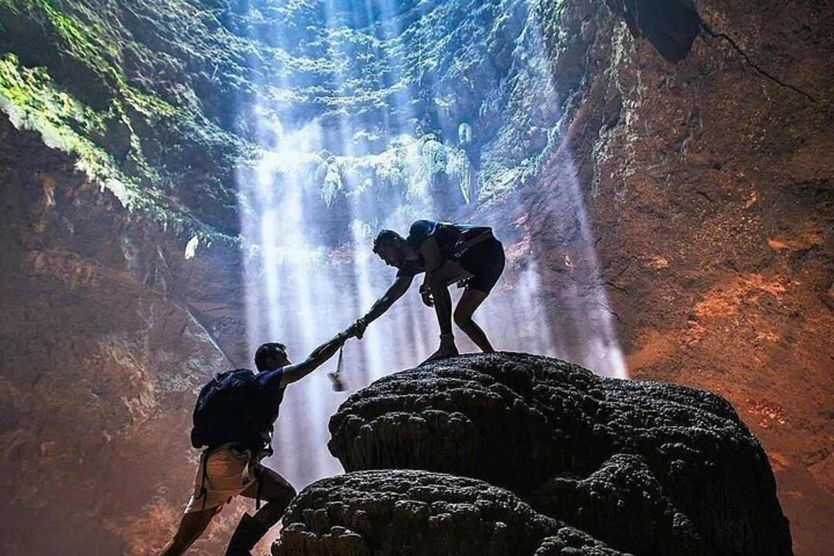 two people are helping each other through a waterfall