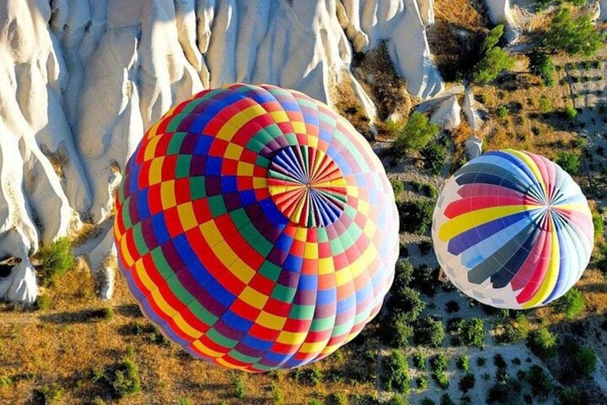 two colorful hot air balloons flying over a field