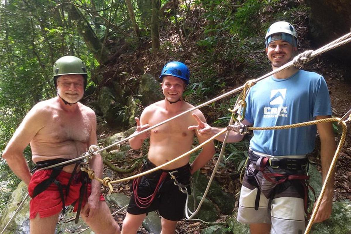 three men on a rope bridge in the jungle