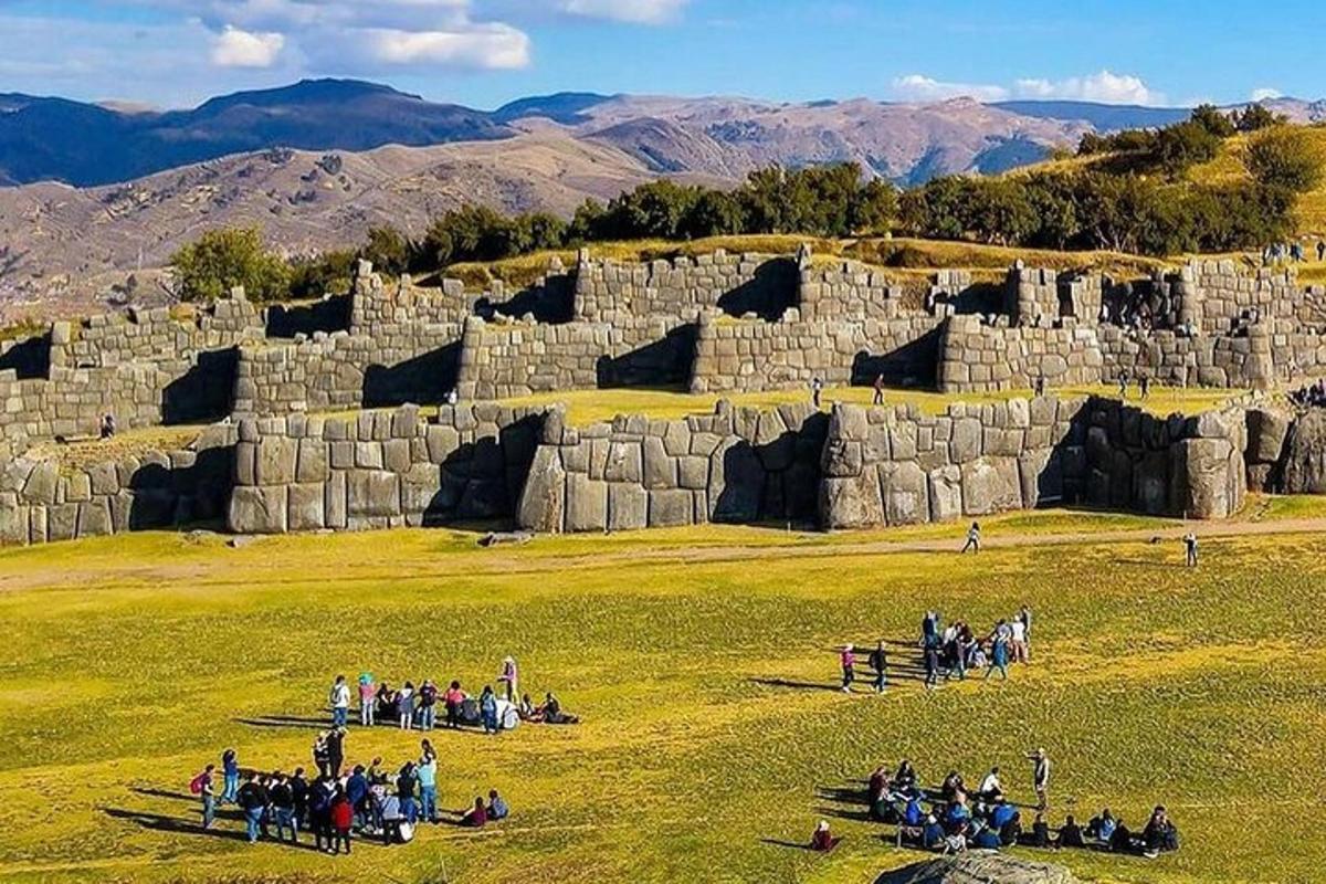 Un grupo de personas de pie en un campo cerca de un muro de piedra.