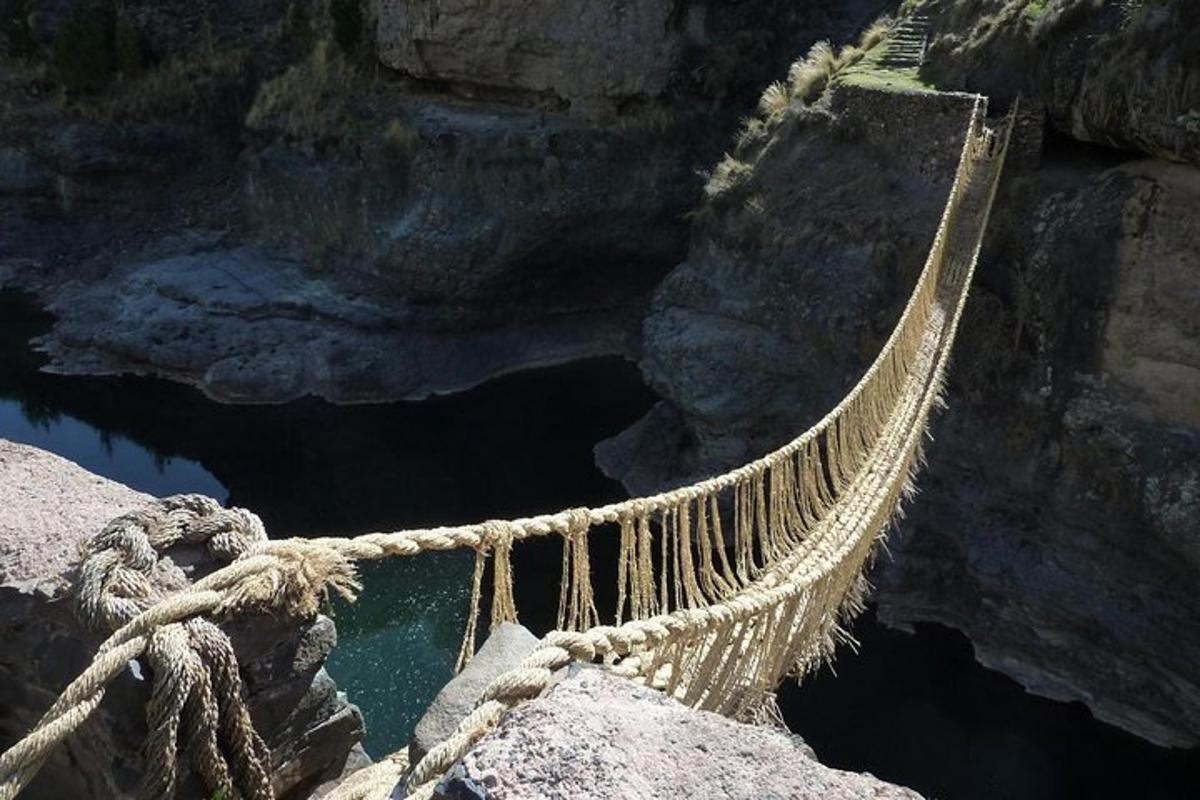 a rope bridge over a pool of water on a cliff