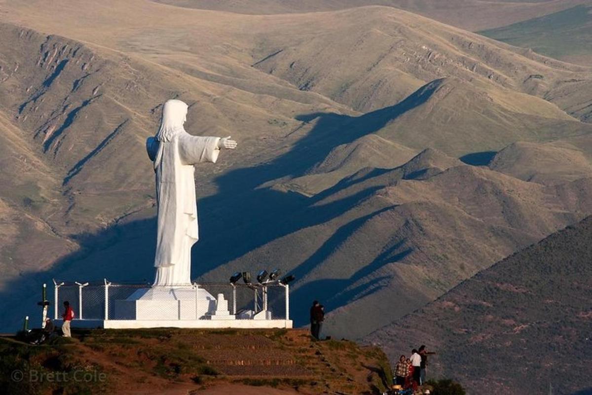 una estatua en la cima de una colina con una montaña