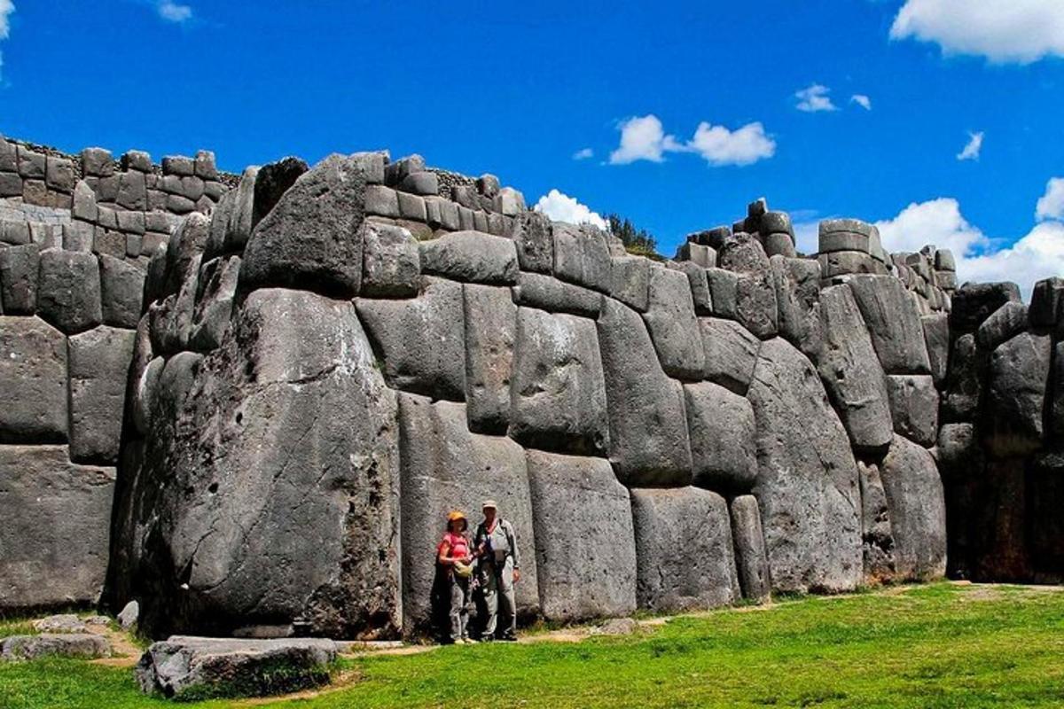 dues persones dempeus davant d'un mur de pedra