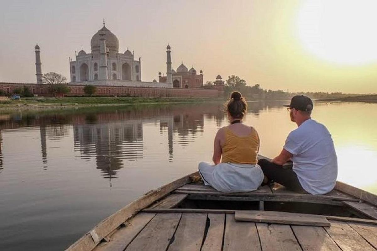 a man and woman sitting in a boat on the water in front of a building