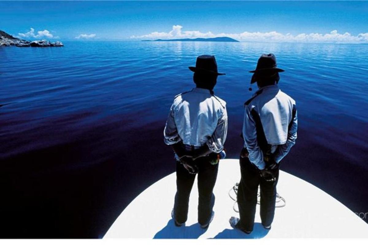 two men standing on the back of a boat in the water