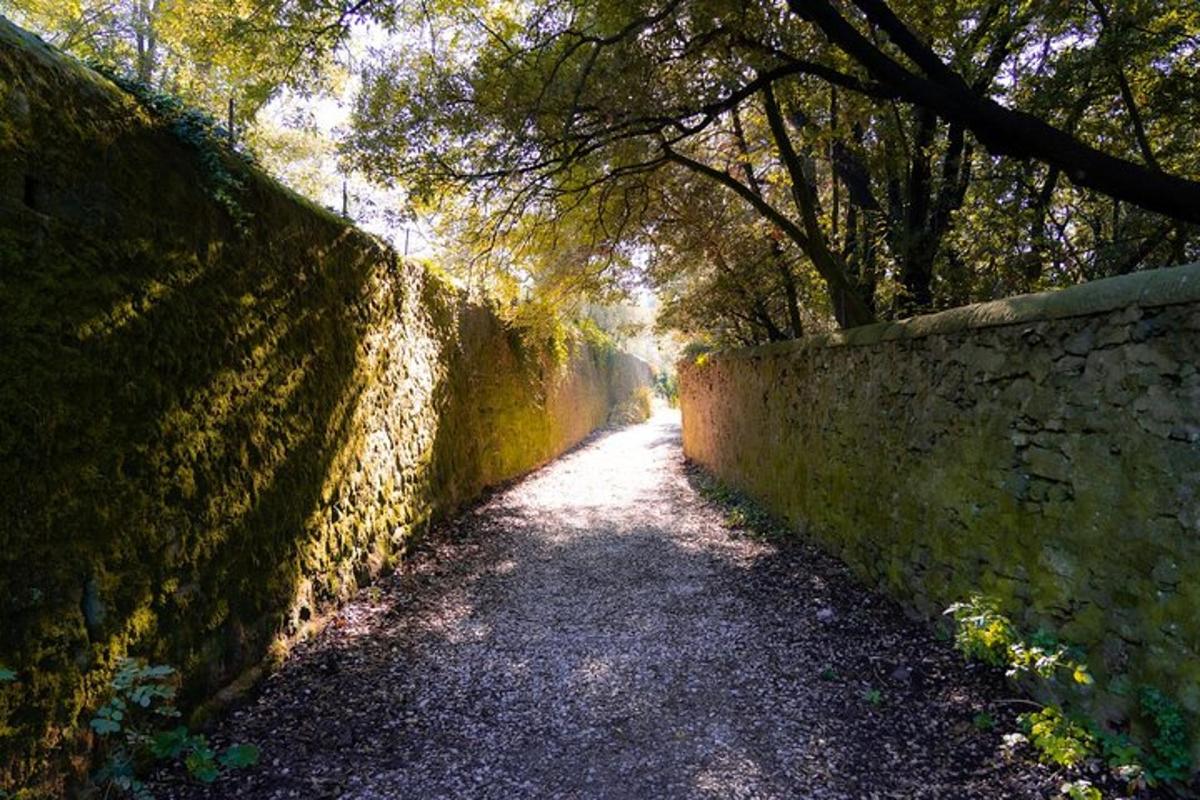 a dirt road next to a stone wall