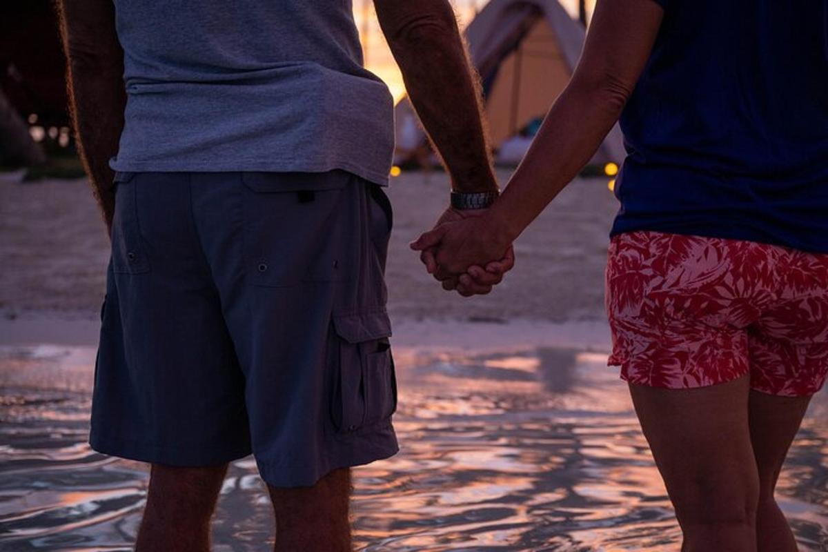 un cuplu ținându-se de mână în timp ce stăteau pe plajă