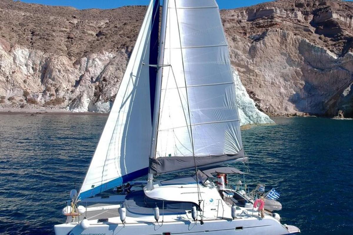 a white sailboat on the water near a mountain