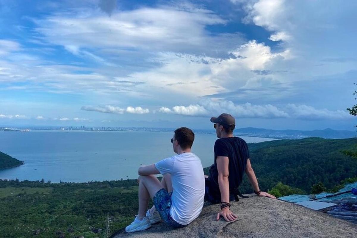 dua lelaki duduk di atas batu yang menghadap ke tasik