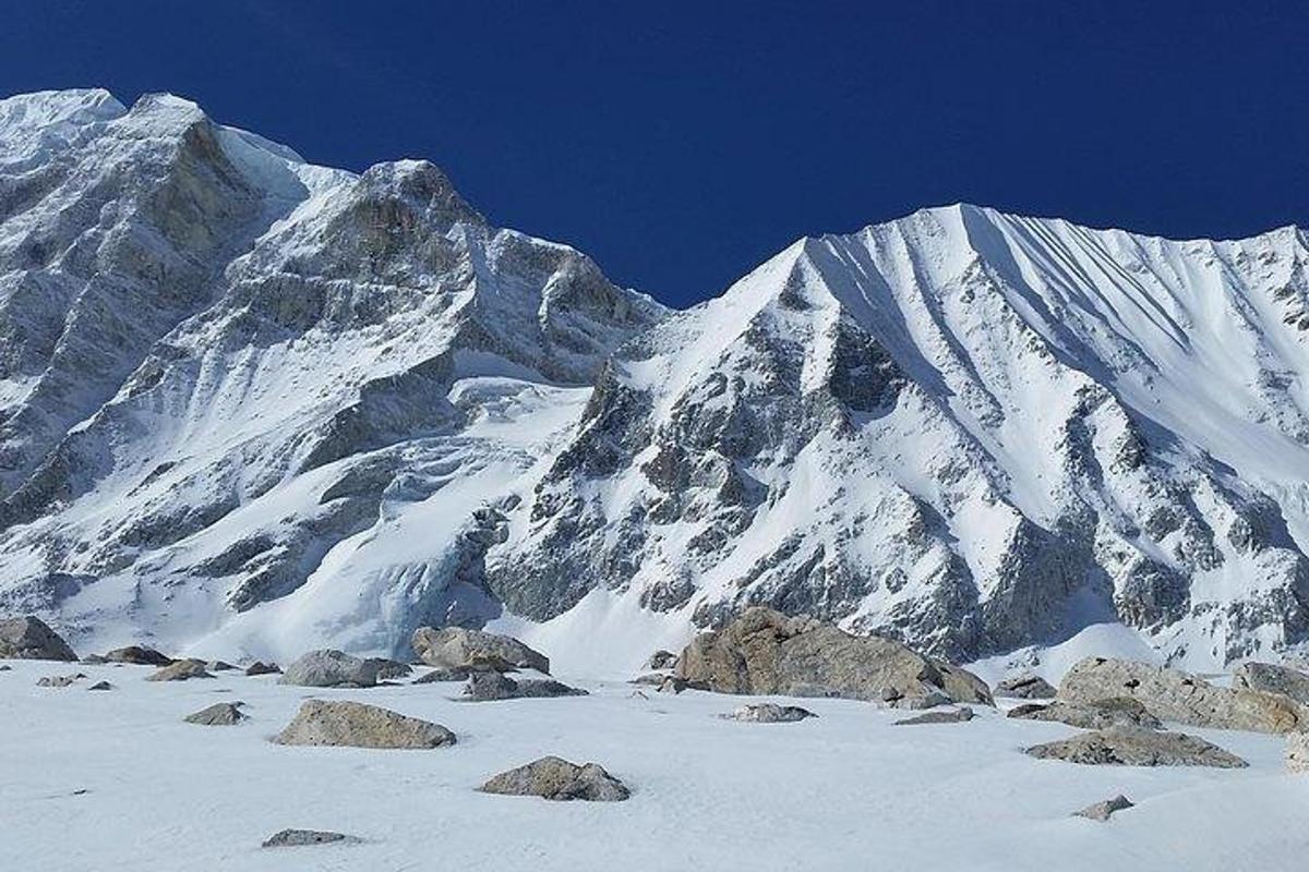 ein schneebedeckter Berg mit Felsen davor