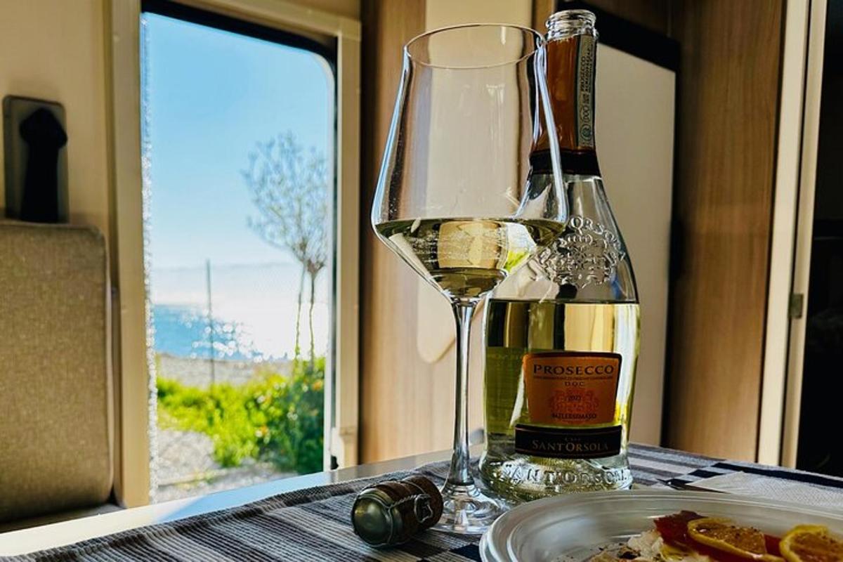 un bicchiere di vino bianco accanto a un piatto di cibo